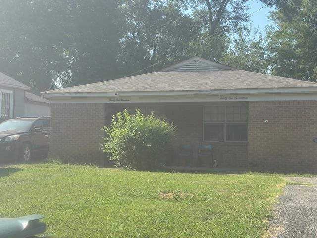 view of side of property with brick siding and a lawn