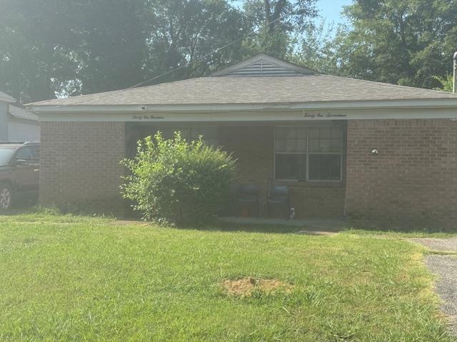 rear view of property featuring a lawn and brick siding