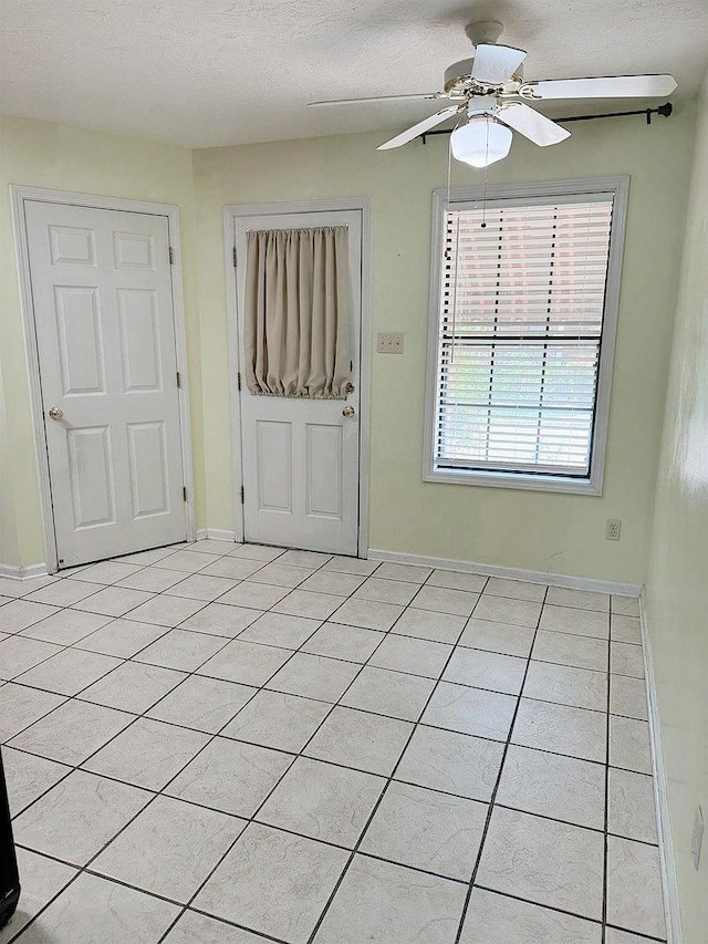 tiled spare room with ceiling fan and a textured ceiling