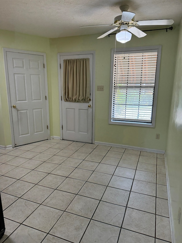 tiled entrance foyer with ceiling fan and a textured ceiling