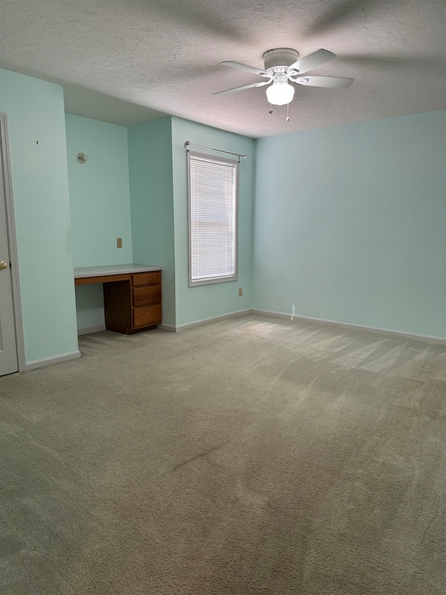 carpeted spare room featuring a textured ceiling and ceiling fan