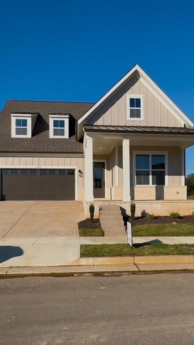 view of front facade with a garage, driveway, roof with shingles, board and batten siding, and brick siding