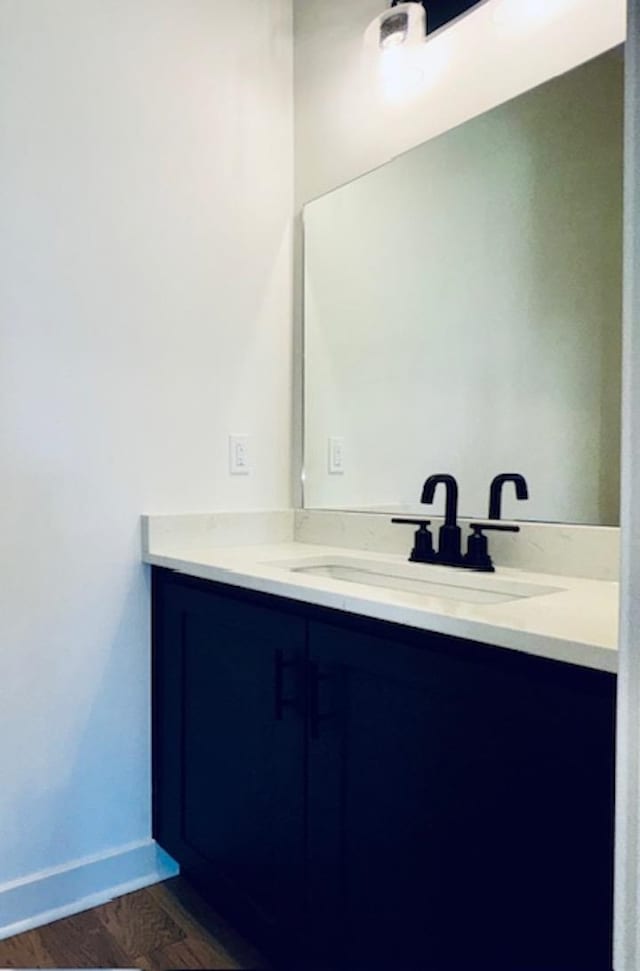 bathroom with wood finished floors, vanity, and baseboards