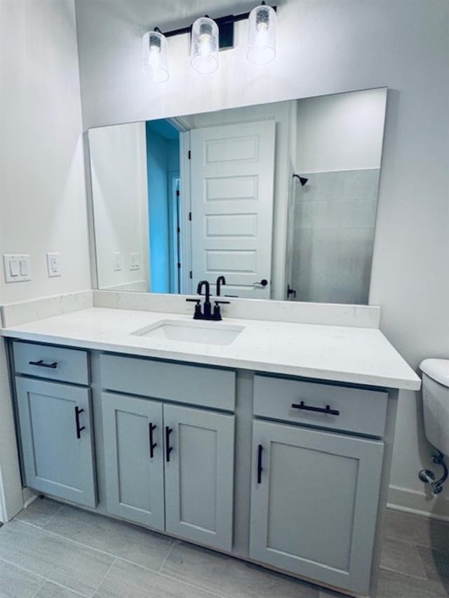 bathroom with toilet, tiled shower, and vanity