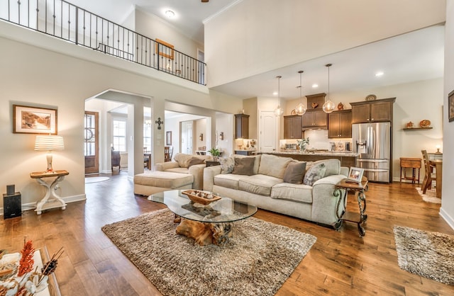 living room featuring ornamental molding, a towering ceiling, and dark hardwood / wood-style floors