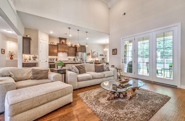 living room featuring a notable chandelier, hardwood / wood-style flooring, and a towering ceiling