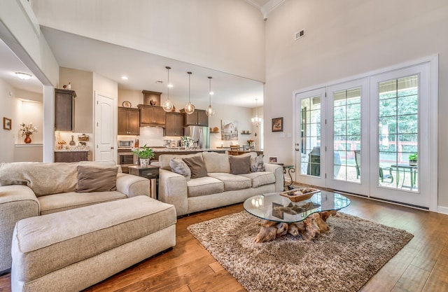 living room with a chandelier, a high ceiling, and hardwood / wood-style floors