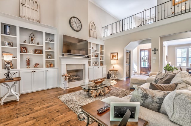 living room featuring a fireplace, wood-type flooring, and a towering ceiling