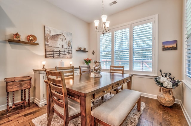 dining area with dark wood-type flooring and an inviting chandelier