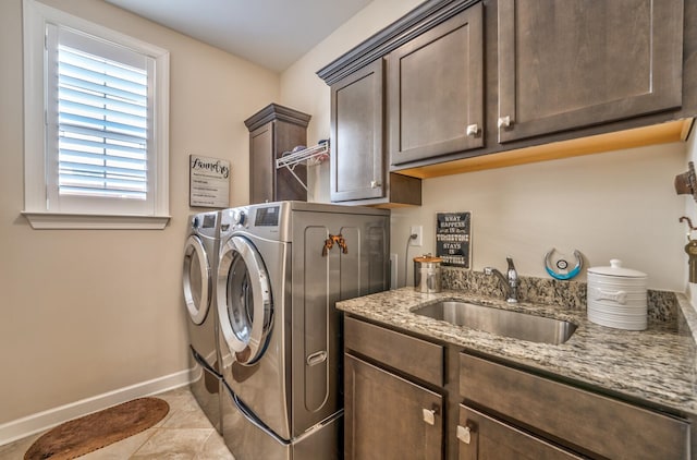 laundry area featuring separate washer and dryer, sink, light tile patterned flooring, and cabinets