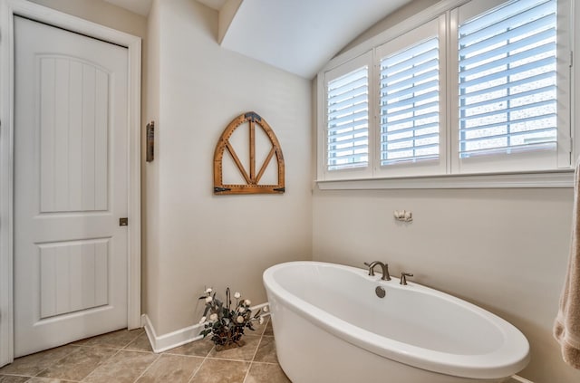 bathroom featuring tile patterned floors, lofted ceiling, a bathtub, and plenty of natural light