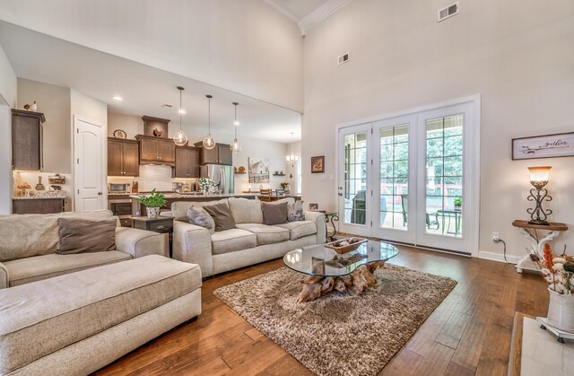 living room featuring a towering ceiling, crown molding, french doors, and dark hardwood / wood-style flooring