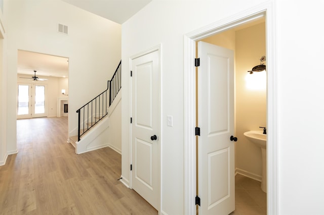 hall featuring light wood-style floors, visible vents, stairway, and baseboards