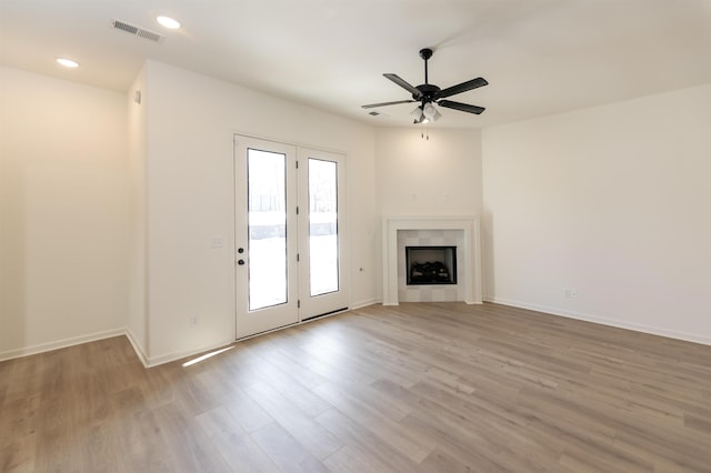 unfurnished living room with ceiling fan, recessed lighting, wood finished floors, visible vents, and a tiled fireplace