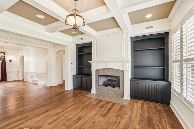 unfurnished living room featuring built in shelves, coffered ceiling, crown molding, hardwood / wood-style flooring, and beam ceiling