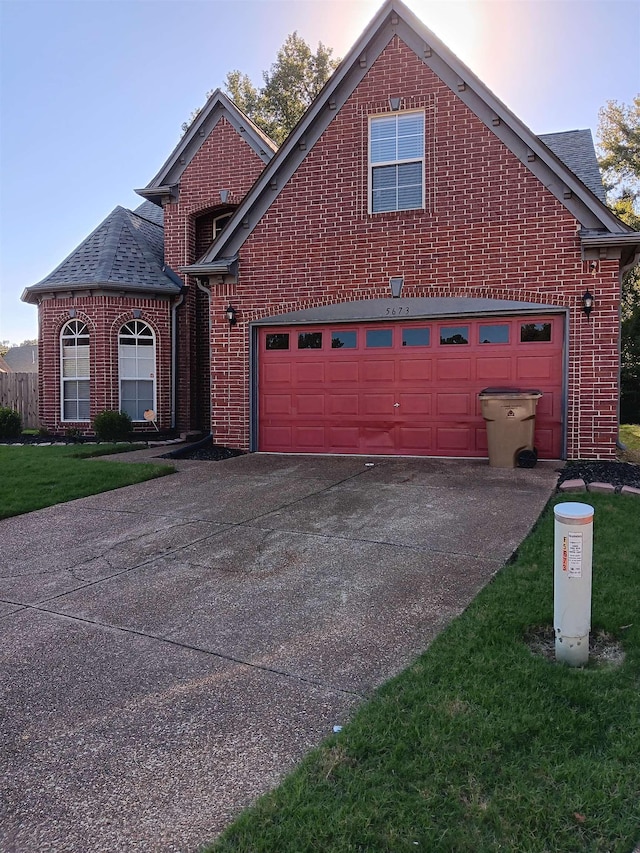 traditional home featuring driveway, roof with shingles, a garage, and brick siding