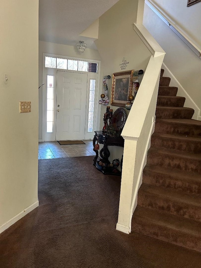 entrance foyer with stairs, tile patterned flooring, carpet flooring, and baseboards