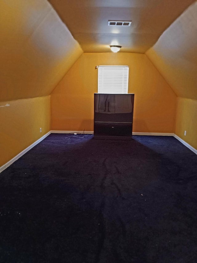 additional living space with baseboards, visible vents, vaulted ceiling, and carpet flooring