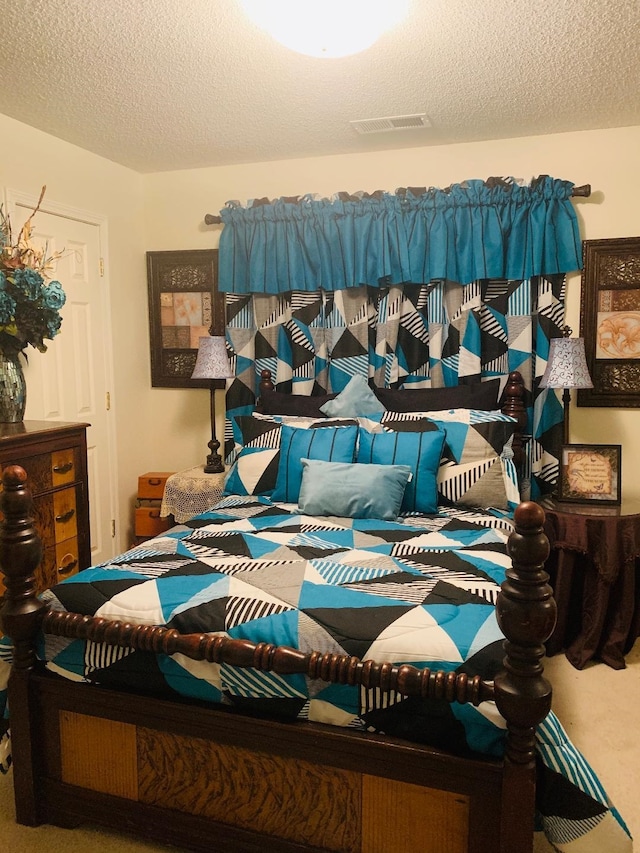 bedroom featuring carpet floors, visible vents, and a textured ceiling