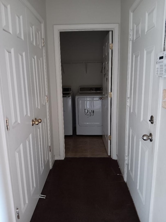 hallway with dark tile patterned flooring and washing machine and clothes dryer