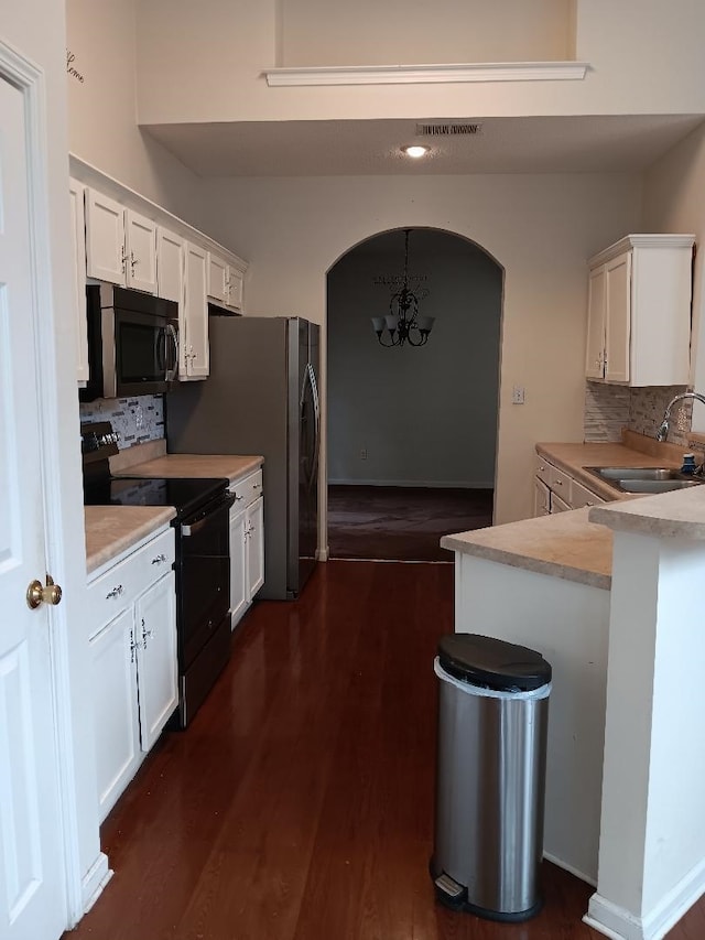 kitchen with electric range, a sink, white cabinets, light countertops, and decorative light fixtures