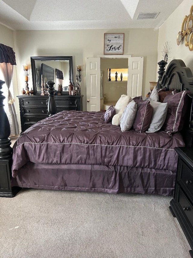 bedroom with a textured ceiling, carpet floors, and visible vents