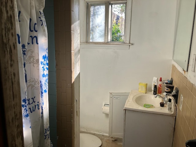 bathroom featuring tile walls, toilet, and vanity