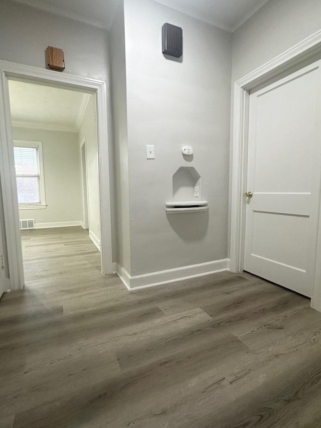 corridor with hardwood / wood-style floors and crown molding