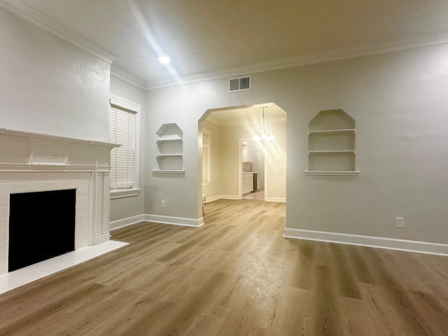 unfurnished living room with wood-type flooring, ornamental molding, and built in shelves