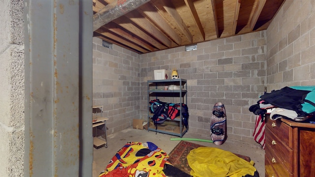 interior space featuring concrete block wall and unfinished concrete floors