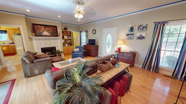 living room featuring ornamental molding, a tile fireplace, and light wood-style floors