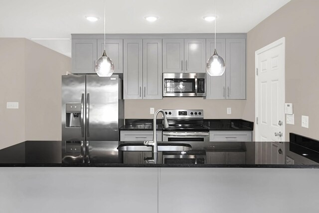 kitchen with dark stone counters, decorative light fixtures, gray cabinetry, stainless steel appliances, and sink