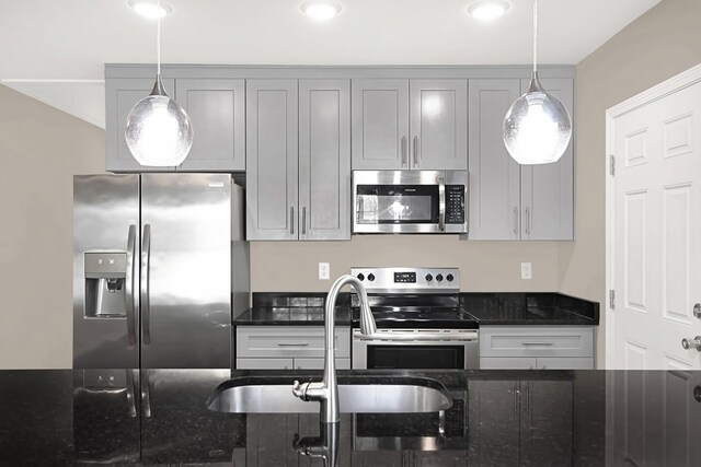 kitchen with appliances with stainless steel finishes, gray cabinets, and dark stone countertops