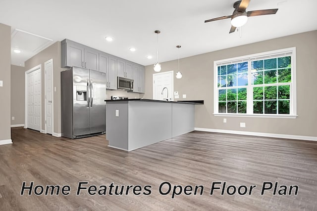 kitchen featuring ceiling fan, appliances with stainless steel finishes, kitchen peninsula, hardwood / wood-style flooring, and pendant lighting