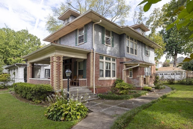 view of front facade featuring a porch, a front yard, and brick siding