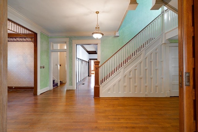 foyer featuring ornamental molding, stairway, baseboards, and wood finished floors