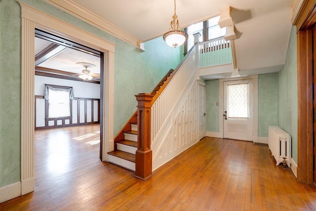 entrance foyer featuring ornamental molding, stairway, wood-type flooring, and radiator