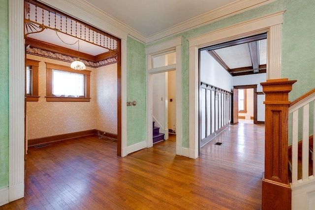 interior space featuring wallpapered walls, baseboards, hardwood / wood-style flooring, stairway, and crown molding