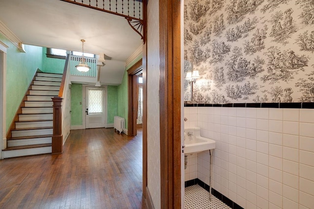 entryway with stairway, wood finished floors, a wainscoted wall, wallpapered walls, and radiator heating unit