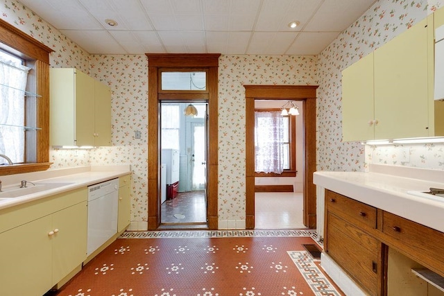 kitchen with wallpapered walls, light countertops, dishwasher, and a sink
