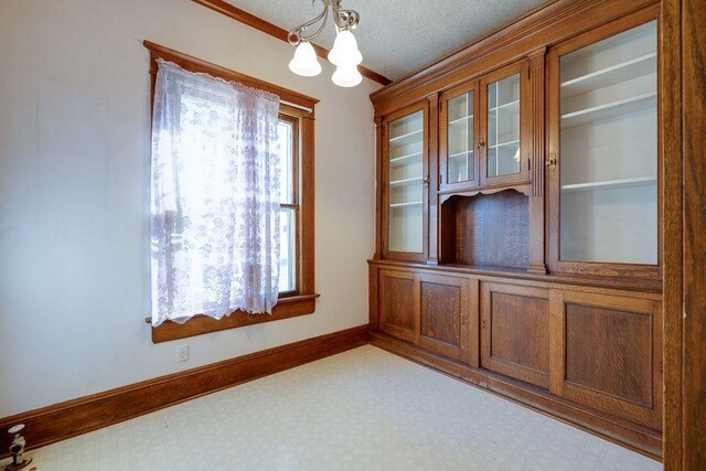 interior space featuring tile patterned floors, a notable chandelier, baseboards, and a textured ceiling