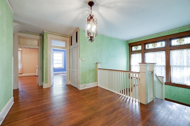 spare room featuring a notable chandelier, wood finished floors, and baseboards