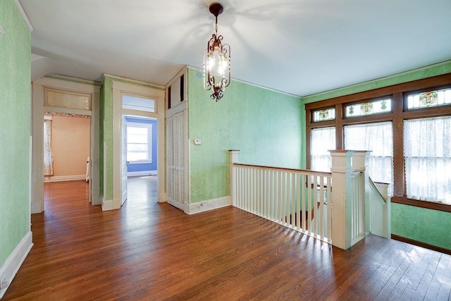 unfurnished room with baseboards, radiator, an inviting chandelier, and wood finished floors