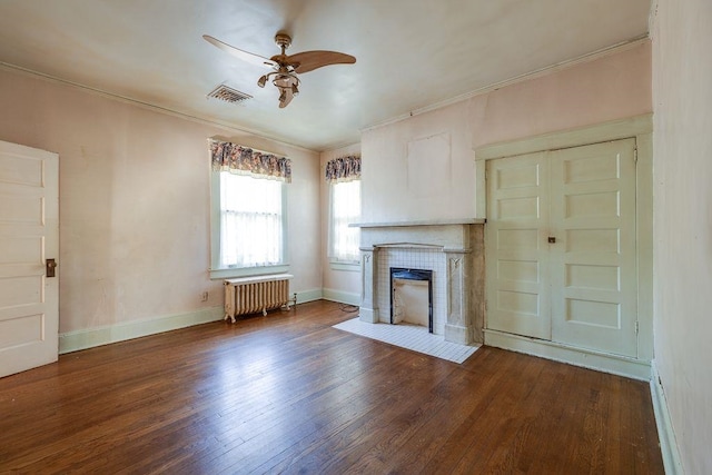 unfurnished living room featuring visible vents, a tiled fireplace, radiator, wood finished floors, and crown molding