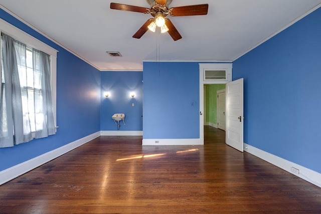 spare room with baseboards, wood finished floors, visible vents, and crown molding