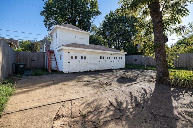 view of property exterior featuring an outbuilding, a detached garage, and fence