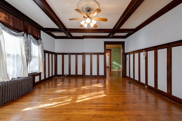 interior space with light wood finished floors, radiator heating unit, ceiling fan, and beam ceiling