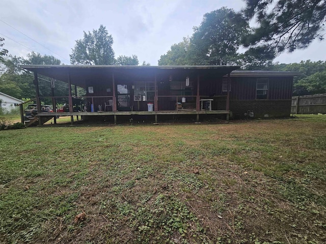 back of property with a deck, a yard, and a sunroom