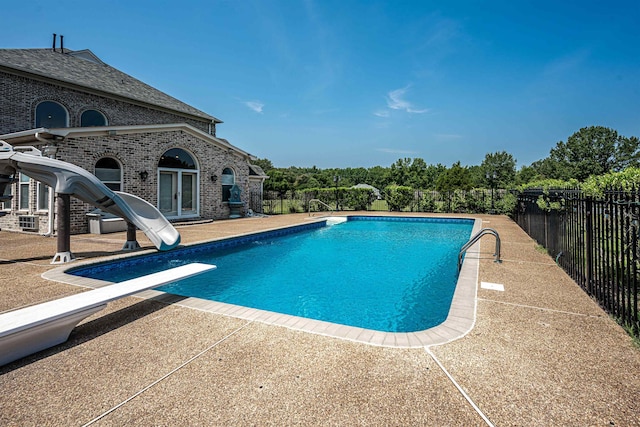 view of pool featuring a patio area, a water slide, and a diving board