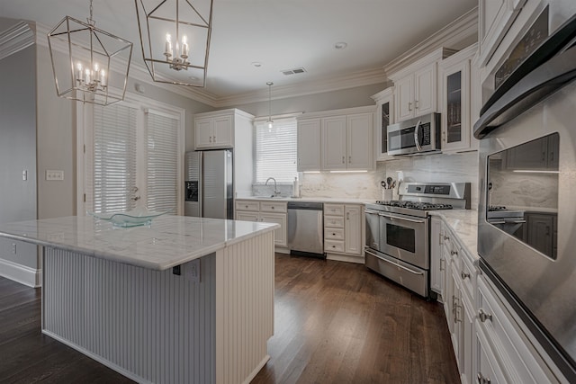 kitchen featuring dark wood-type flooring, decorative backsplash, a kitchen island, white cabinetry, and stainless steel appliances